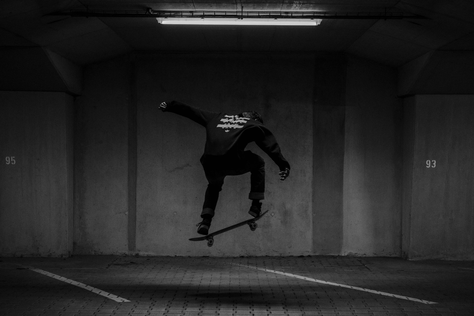 man in black and white long sleeve shirt and black pants jumping on gray concrete floor